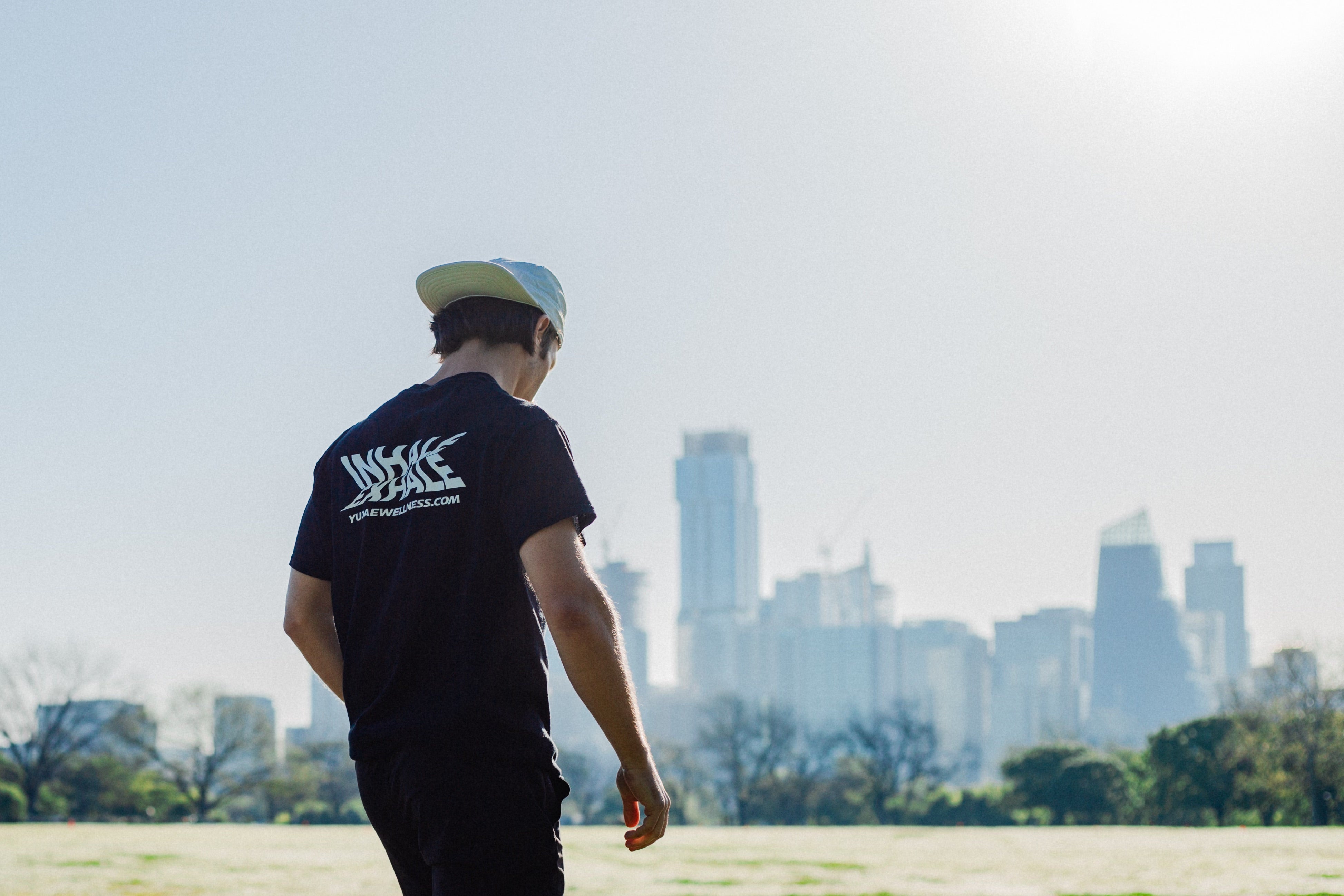 Man walking through Zilker Park in Austin Texas wearing a Yudae Wellness Inhale Exhale t-shirt