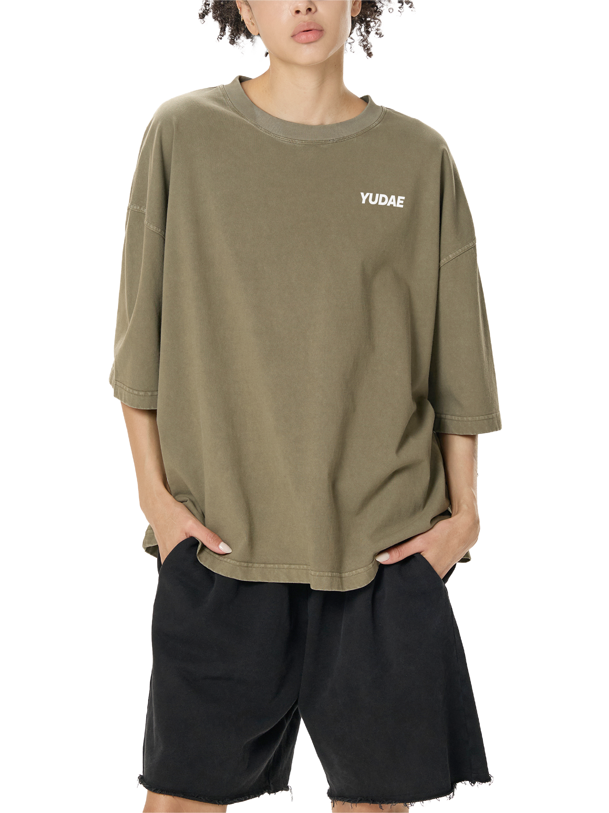 Person wearing an olive green oversized t-shirt with 'YUDE' logo and black shorts on a white background