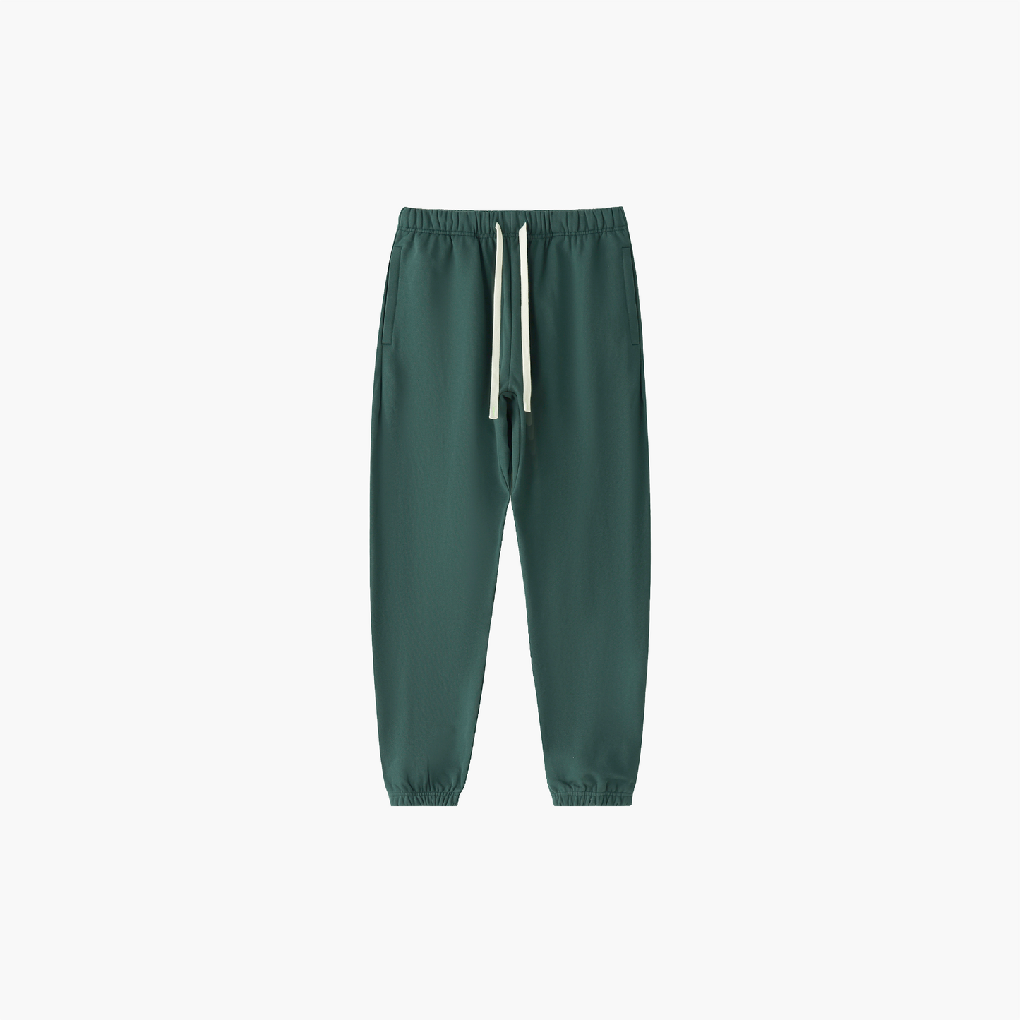 Green jogger pants with a white drawstring on a light beige background